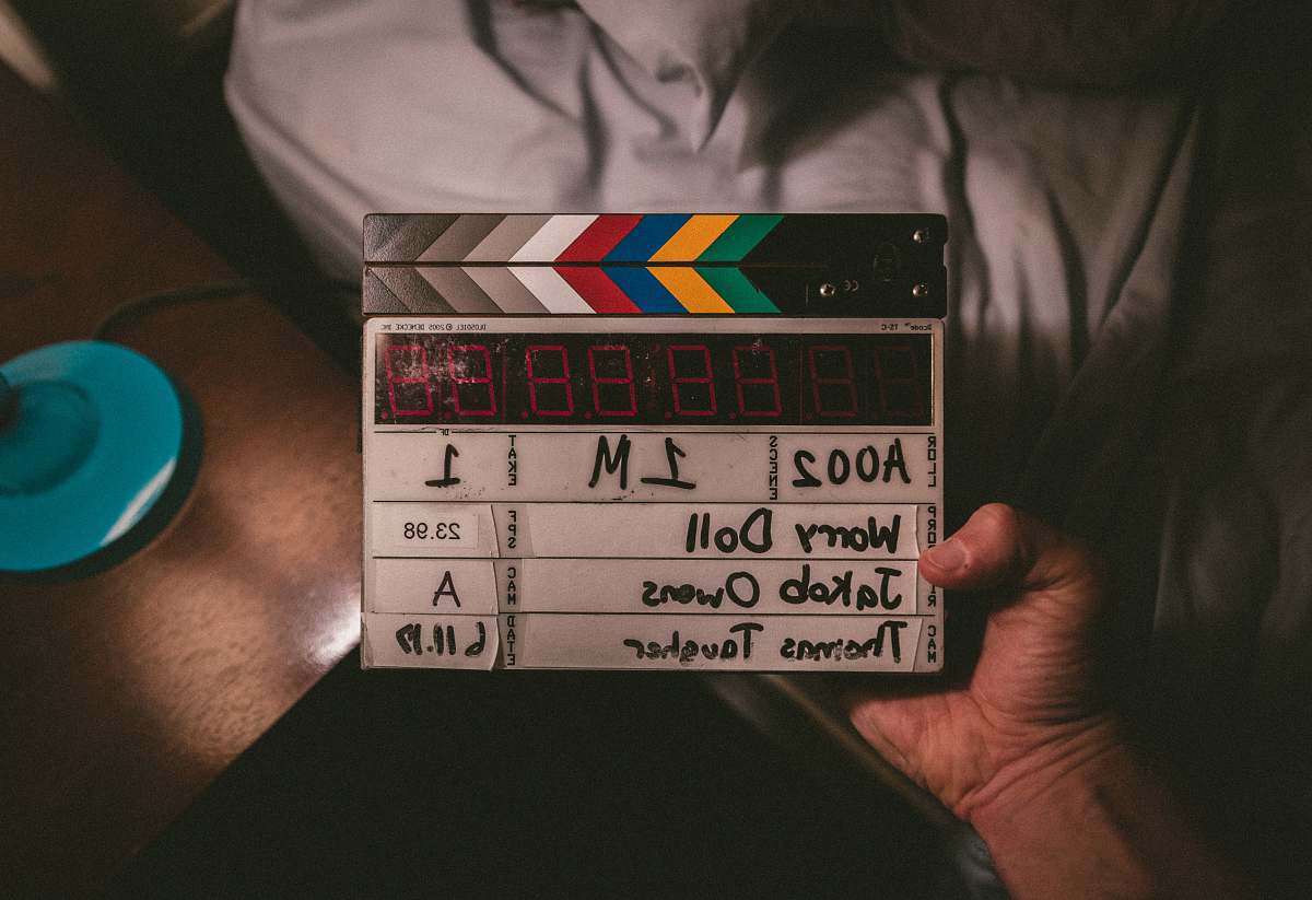 film camera person holding Worry doll time clapper flat flay